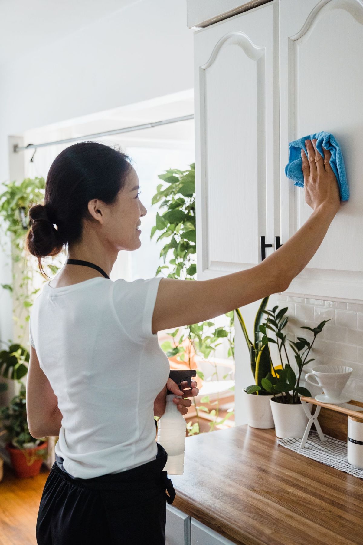 CleanKaki cleaner wiping down kitchen cabinets with a cloth